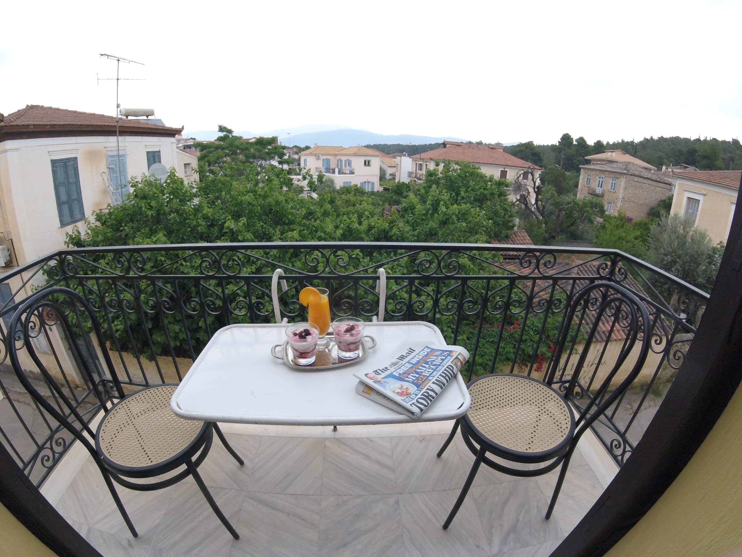 Yoghurt, juice and a newspaper on a balcony table overlooking the rooftops of Galaxidi